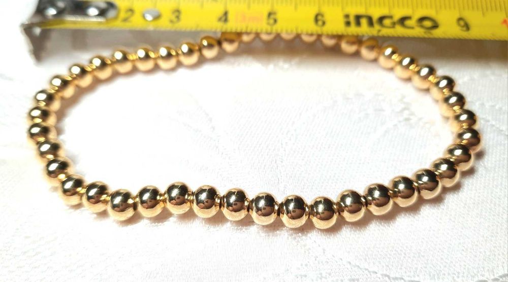 Браслет золотистими кульками на лісці, що тягнеться, дуже милий