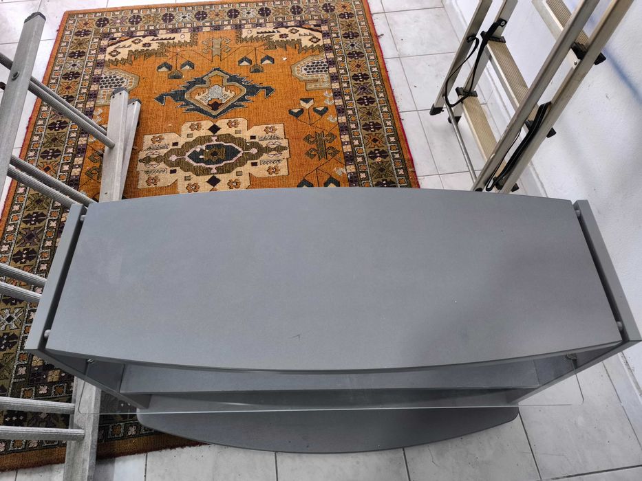 Móvel de Tv cinzento com prateleira em vidro.