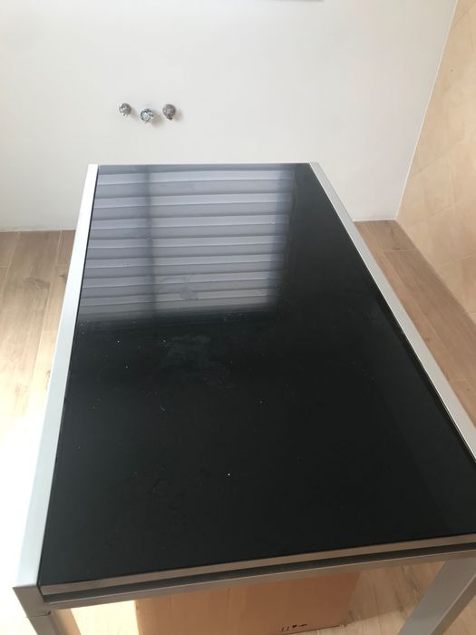 Mesa de vidro de cor preta. A mesa e de abrir. Mede 1,20 por 0,68.