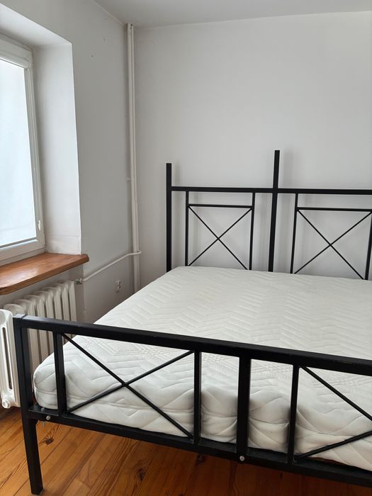 Łóżko z metalową ramą i materacem.