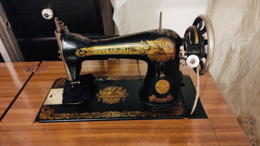 máquina de costura Singer antiga em móvel com pedal - icónico decalque dourado “Sphinx”