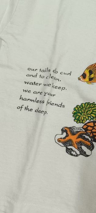 T-shirt branca com bonecos do mar. Tem cavalo marinho a 3D