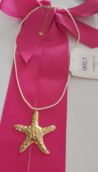 Colar dourado, em aço, com pingente em forma de estrela. Tem extensor