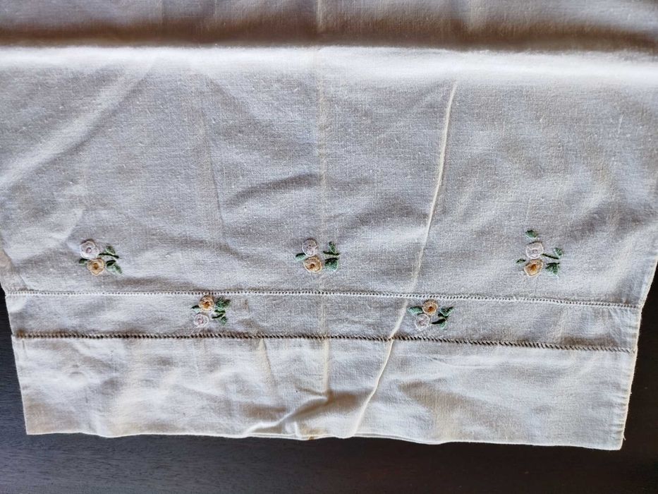 Lençol e almofada com flores bordadas a mão.