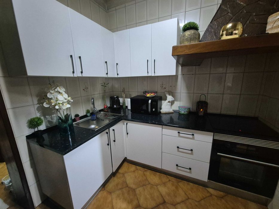 Balcão de cozinha juntamente com armários e um sofá com mesa