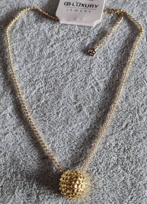 Colar dourado, em aço, com meia bola toda trabalhada. Tem extensor