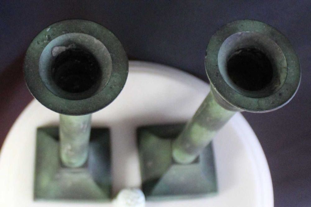 Par de castiçais antigos de latão com pátina esverdeada.