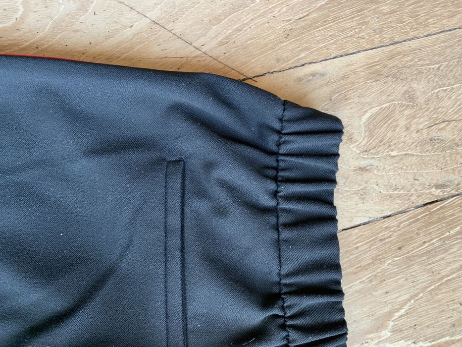 Calças pretas com riscas brancas e encarnadas de lado