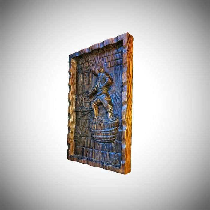 Drewniana płaskorzeźba - postać przy tradycyjnym depczeniu winogron