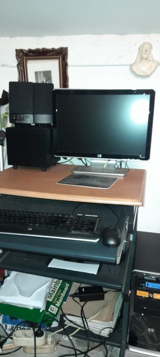 Computador HP, impressora, sistema de som e secretária.