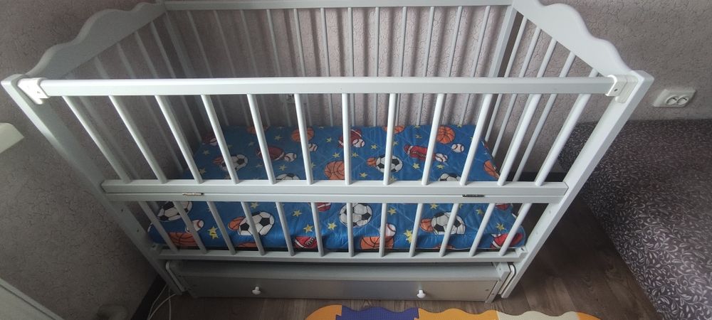 Дитяча кроватка з шухлядками і матрасом.