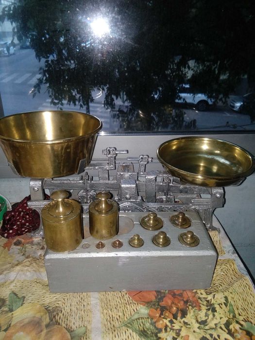 Vintage two-pan balance made of copper with a base containing 11 weights