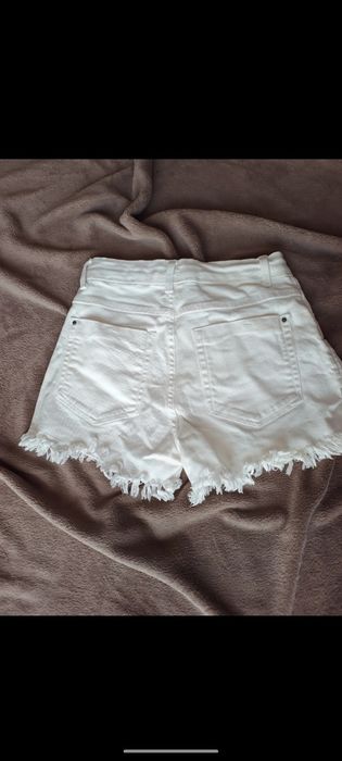 Białe strzępione spodenki
