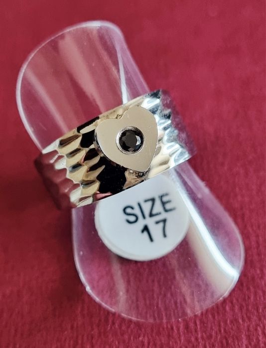 Anel prateado, em aço, com 1 coração com pedrinha preta no centro. T17