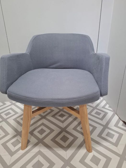 Nowoczesny szary fotel z duzym siwdziskiem na drewnianej podstawie