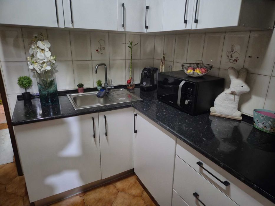 Balcão de cozinha juntamente com armários e um sofá com mesa