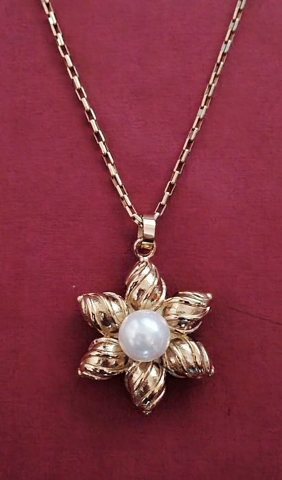 Colar dourado, em aço, flor com pérola. Tem extensor