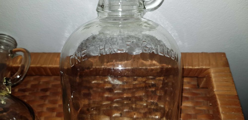 Garrafões de vidro com pega "ONE GALLON" e "ONE HALF GALLON"