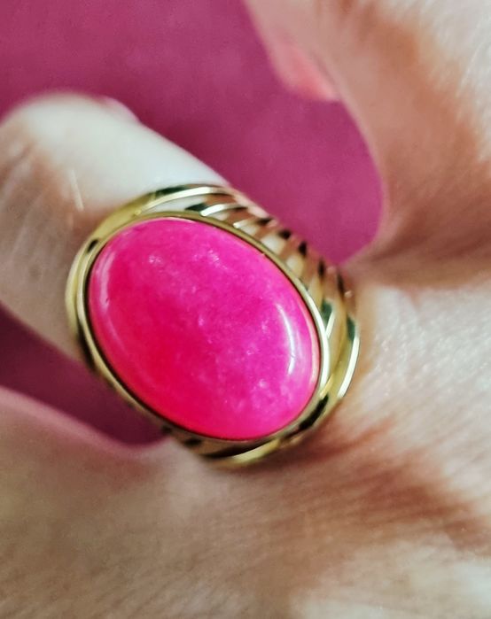 Anel dourado, em aço, com pedra oval rosa fucsia. 18/ajustável