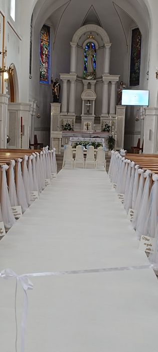 dekoracje ławek, biały dywan, biały klęcznik, kompozycje kwiatowe, świeczniki i dekoracje świetlne, płatki róż, kompleksowa aranżacja