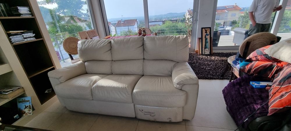Sofá em pele genuína de três lugares, cor creme, equipado com sistema reclinável e apoio de pés num dos lugares. Muito confortável para sala de estar