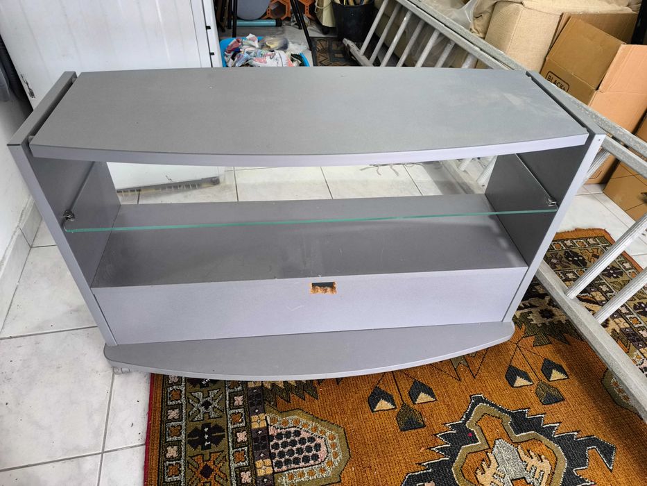 Móvel de Tv cinzento com prateleira em vidro.