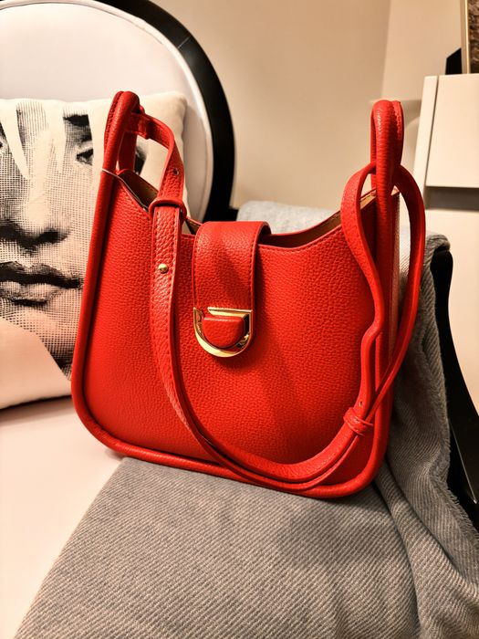 Mala nova, de cor vermelha, com alça à tiracolo.