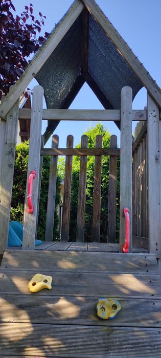 Zjeżdżalnia z małym domkiem i ścianką   wspinaczkową.