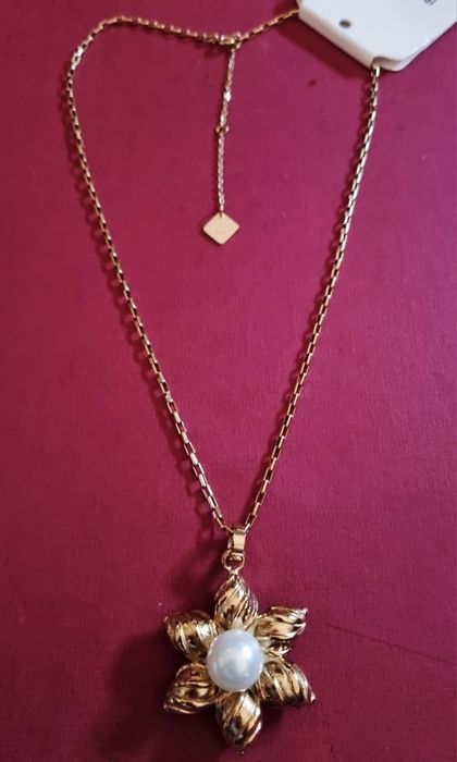 Colar dourado, em aço, flor com pérola. Tem extensor