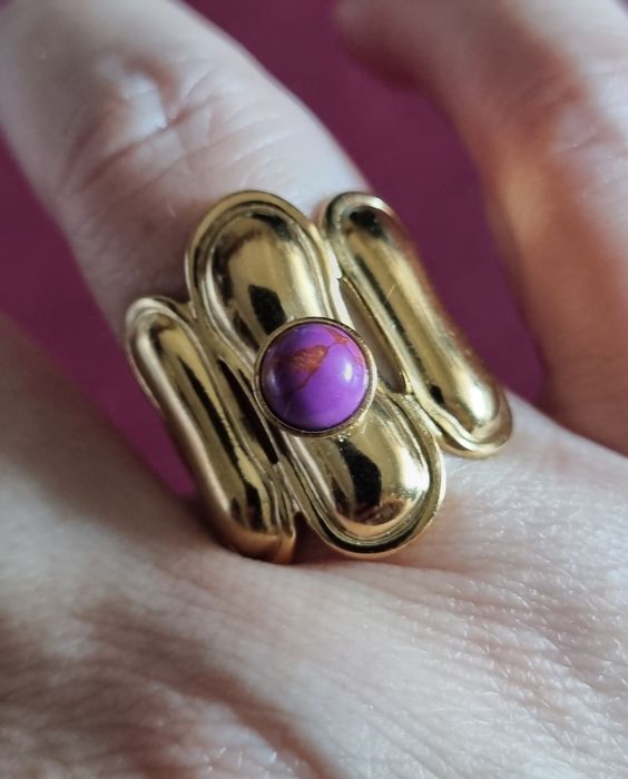 Anel dourado, em aço, com pedrinha redonda lilás. Ajustável