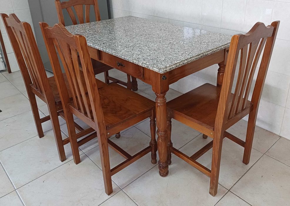 Mesa de cozinha com tampo em granito polido e quatro cadeiras.