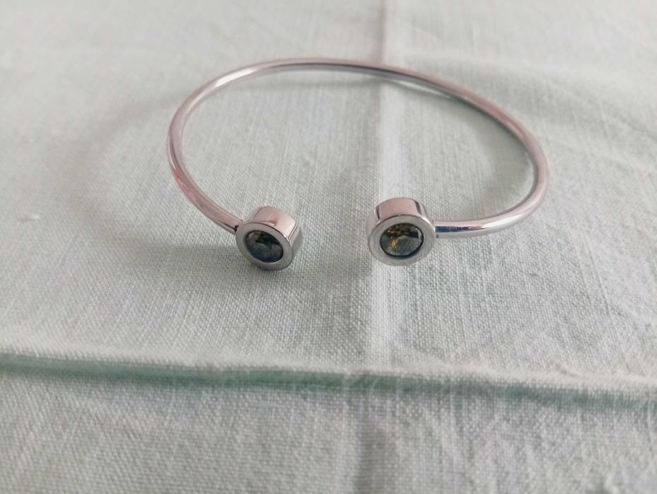 Pulseira, tipo escrava, em metal prateado e detalhes com pedra verde, nas pontas