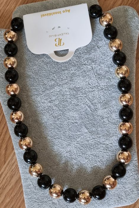 Colar dourado, em aço, às bolinhas douradas intercaladas com pretas. Leve.