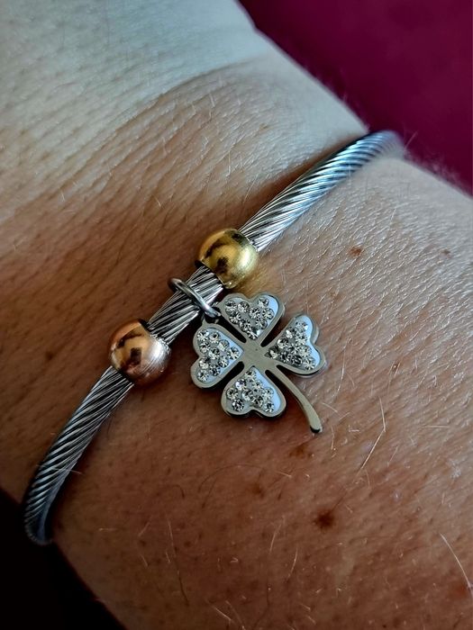 Pulseira prateada, em aço, com bolinhas douradas e um trevo da sorte.