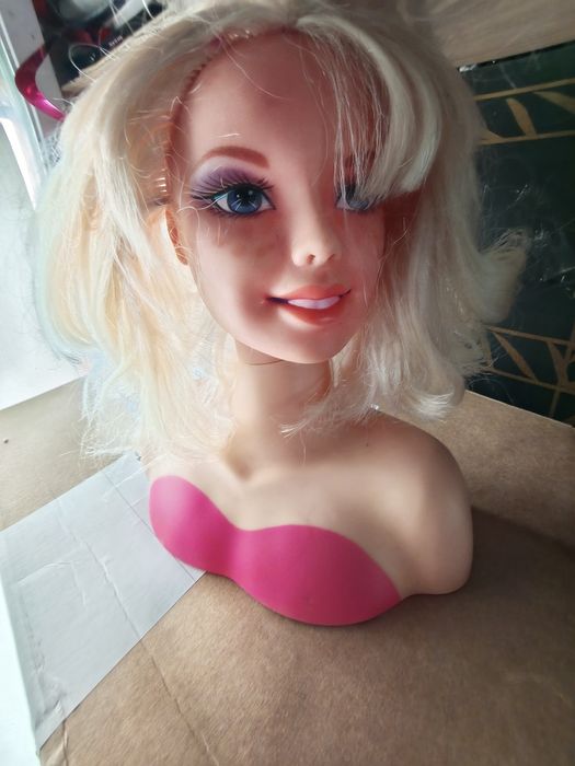 Ta głowa lalki do stylizacji Barbie marki Mattel posiada blond włosy i makijaż w odcieniach fioletu