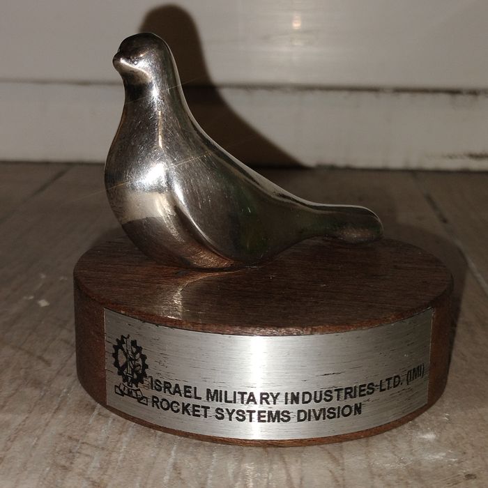 srebrna figurka ptaka (symbolu pokoju) na drewnianym stojaku