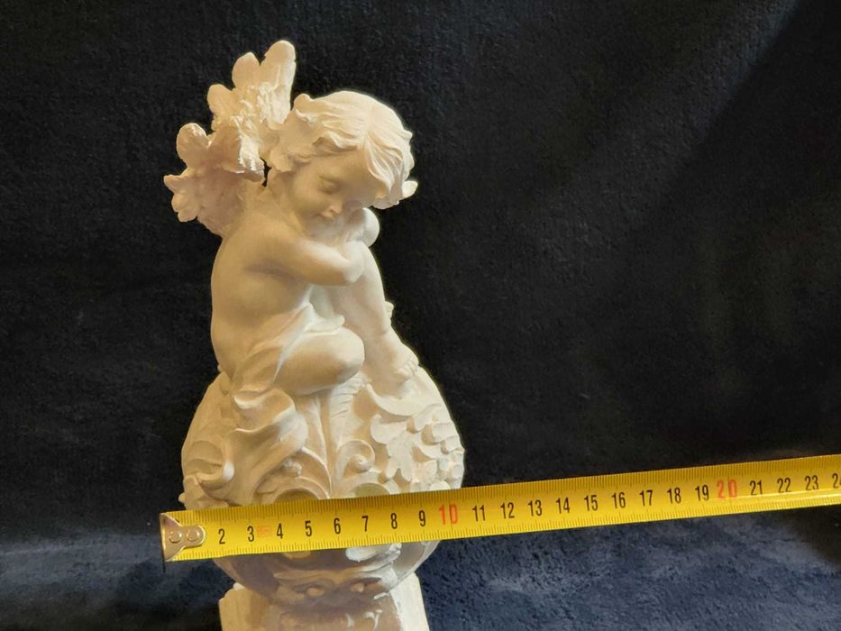 Querubim (anjo-bebé) sentado numa esfera ornamentada em Marfinite
