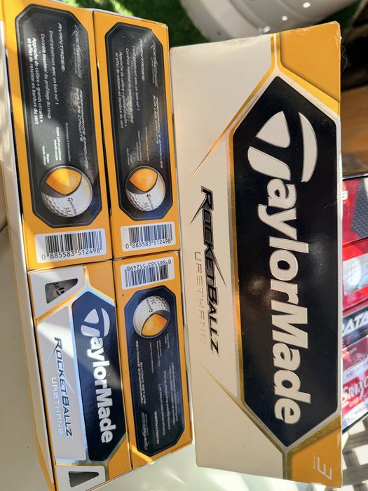 Bolas de golfe novas nas caixas e de treino