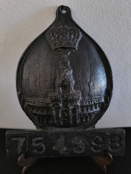 Placa de metal com o n.º 754398, marcada com o emblema da seguradora
