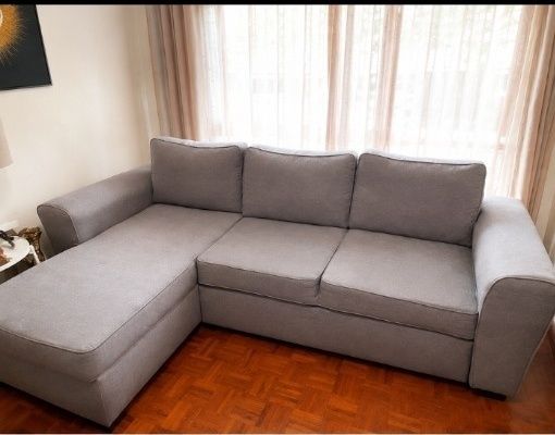 Sofá chaise longue em tecido cinzento, usado mas em bom estado geral.