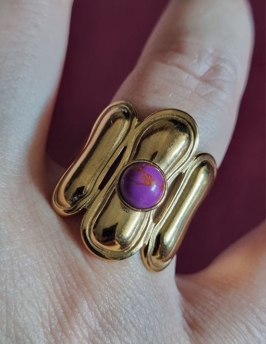 Anel dourado, em aço, com pedrinha redonda lilás. Ajustável