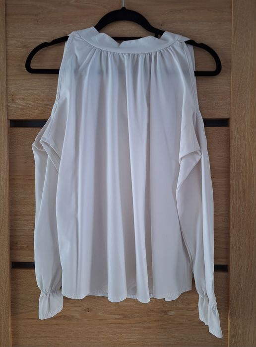 Biała bluzka z wycięciem na ramiona i ozdobnym wiązaniem na tyle