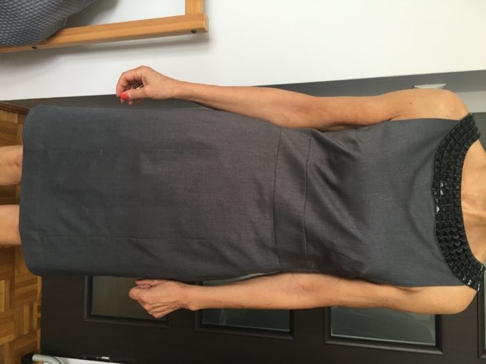 Elegancka szara sukienka marki H&M ze zdobieniem przy dekolcie.