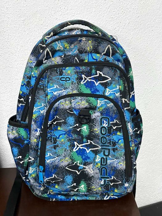 Mochila escolar CoolPack em tons azul, verde e preto, com padrão de tubarões.