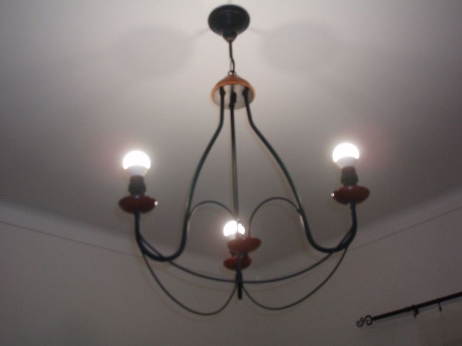 cama de ferro com mesa de cabeceira e candiero de teto