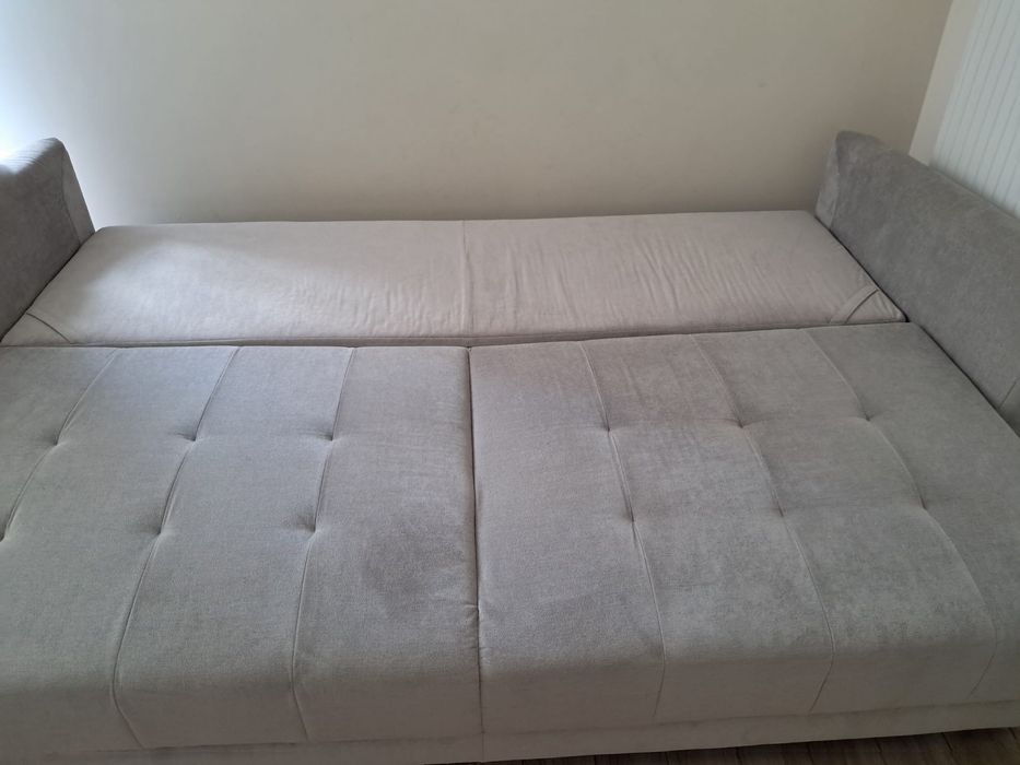 Szara sofa rozkładana z pojemnikiem na pościel