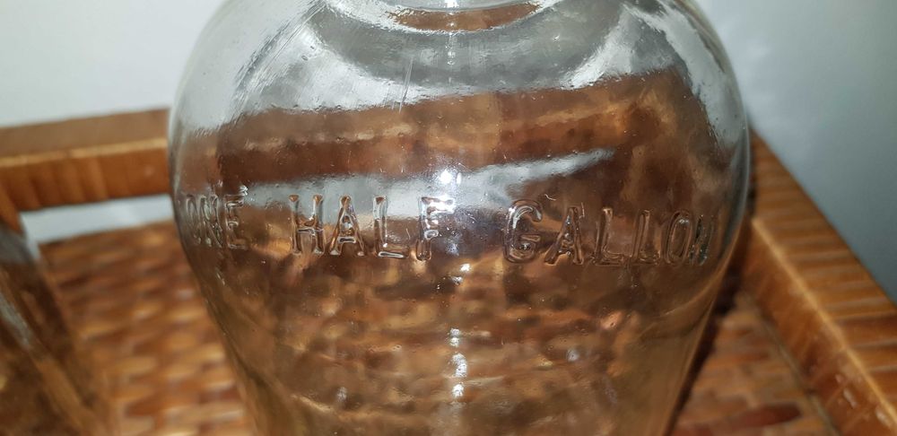 Garrafões de vidro com pega "ONE GALLON" e "ONE HALF GALLON"