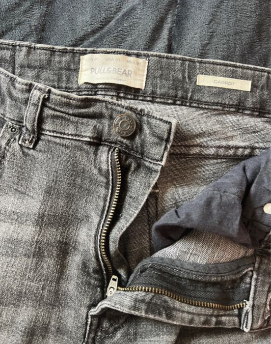 Calças de ganga cinza escura, com detalhes de rasgos