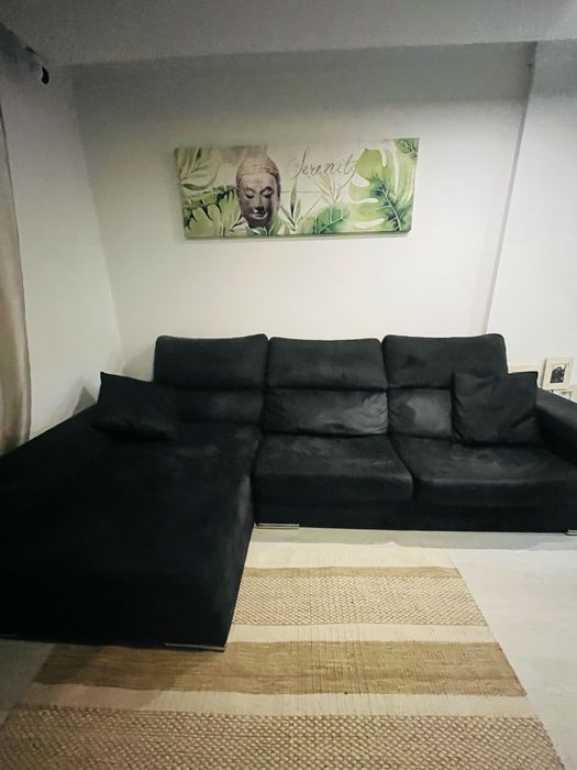 Sofá preto chaise longue, com arrumacão e 2 bancos