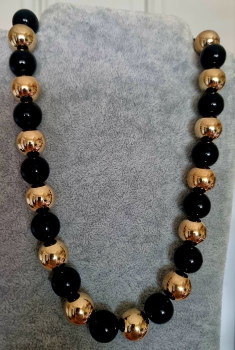 Colar dourado, em aço, às bolinhas douradas intercaladas com pretas. Leve.